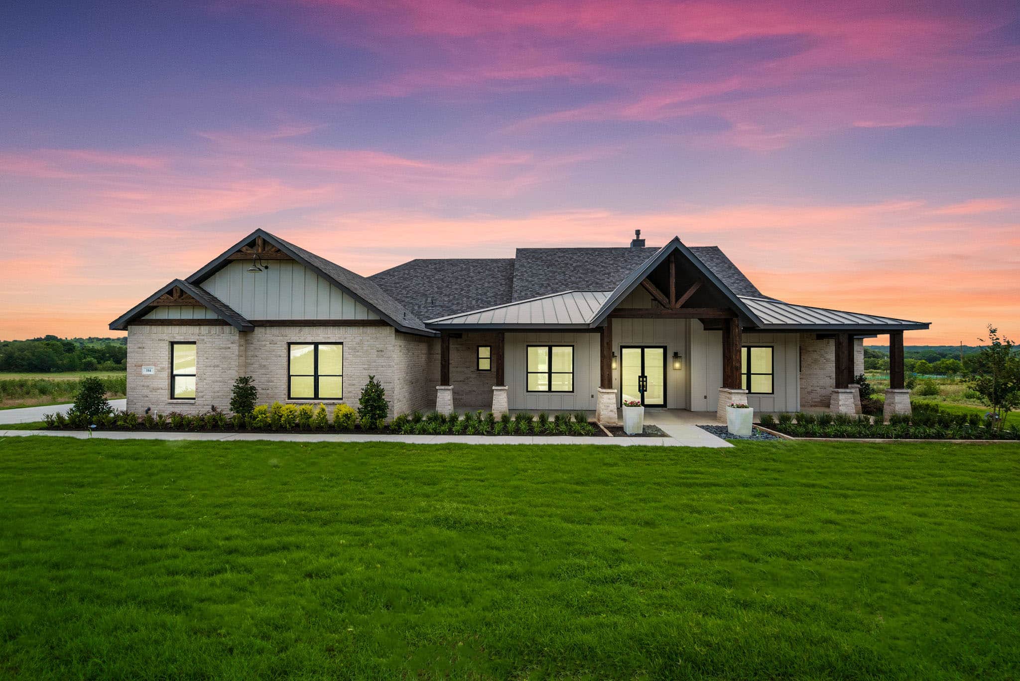 New home modern farmhouse exterior with brick and board-and-batten siding, covered front porch, and sunset sky in West Texas and Dallas–Fort Worth.