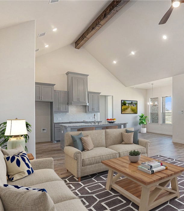 Bright open-concept living room and kitchen with vaulted ceiling, modern gray cabinets, neutral sofa seating, and wood coffee table in a new construction home.