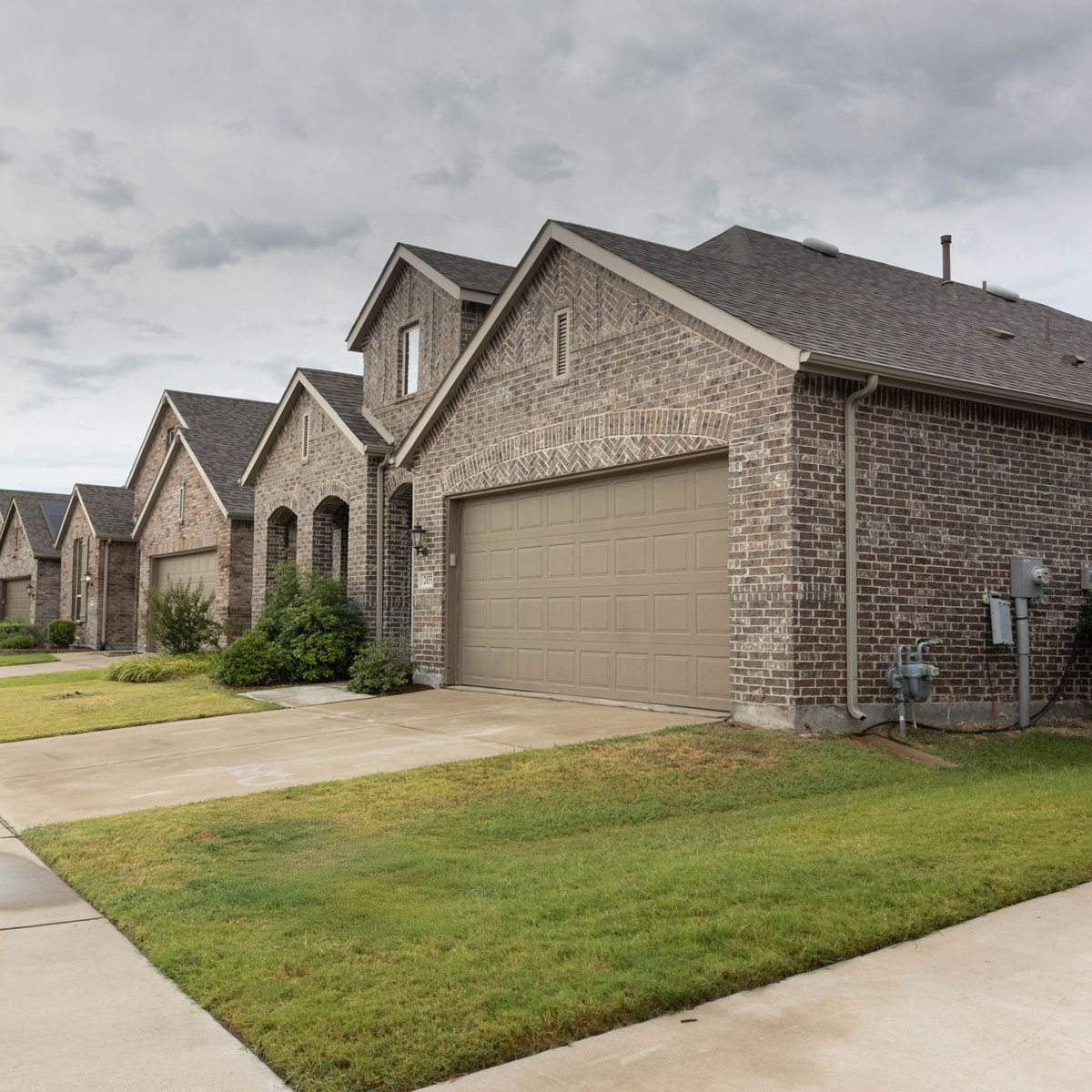 Row of brick single-family homes with attached garages in a West Texas neighborhood.